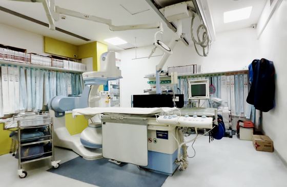 Cath lab with a C-arm fluoroscopy unit over the procedure table