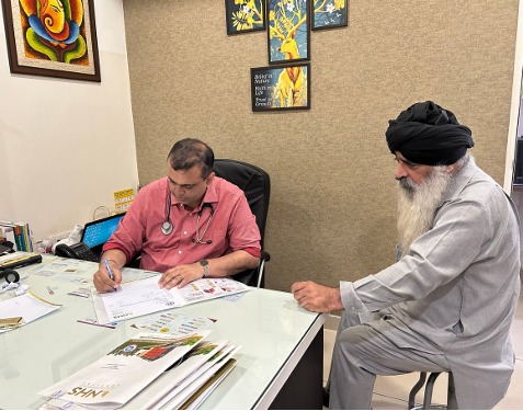An NHS Hospital consultant reviewing an elderly patient's reports across the desk during an OPD consultation