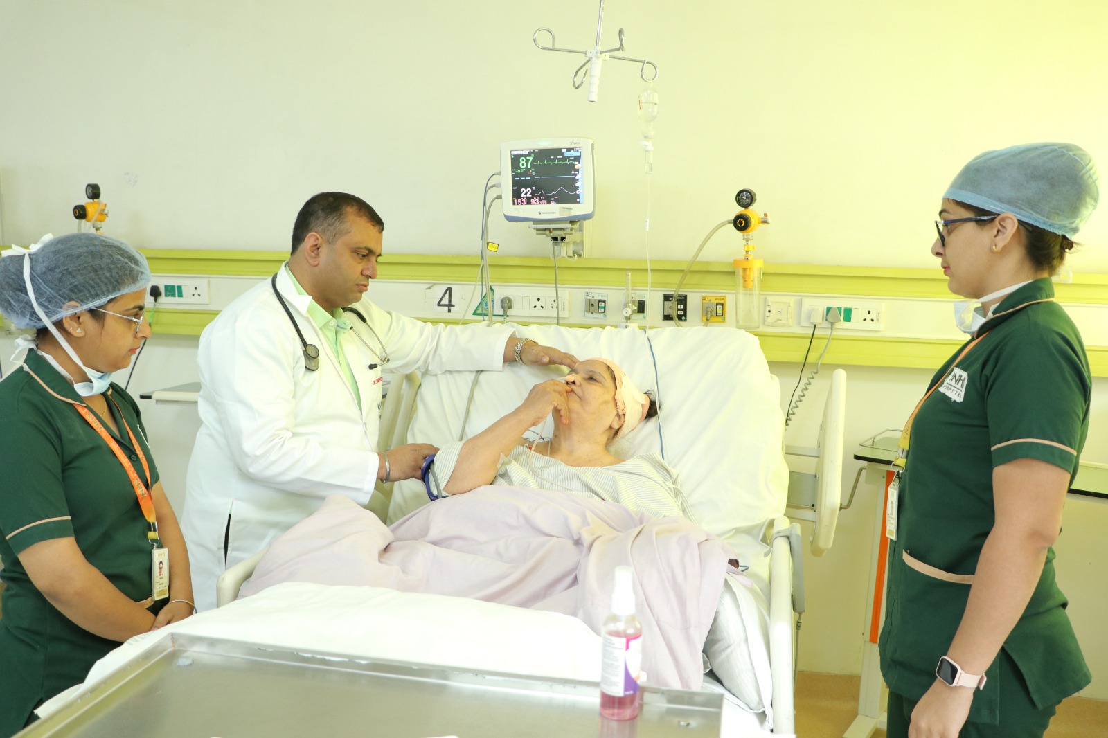 Doctor and two nurses attending a patient in a ward bed